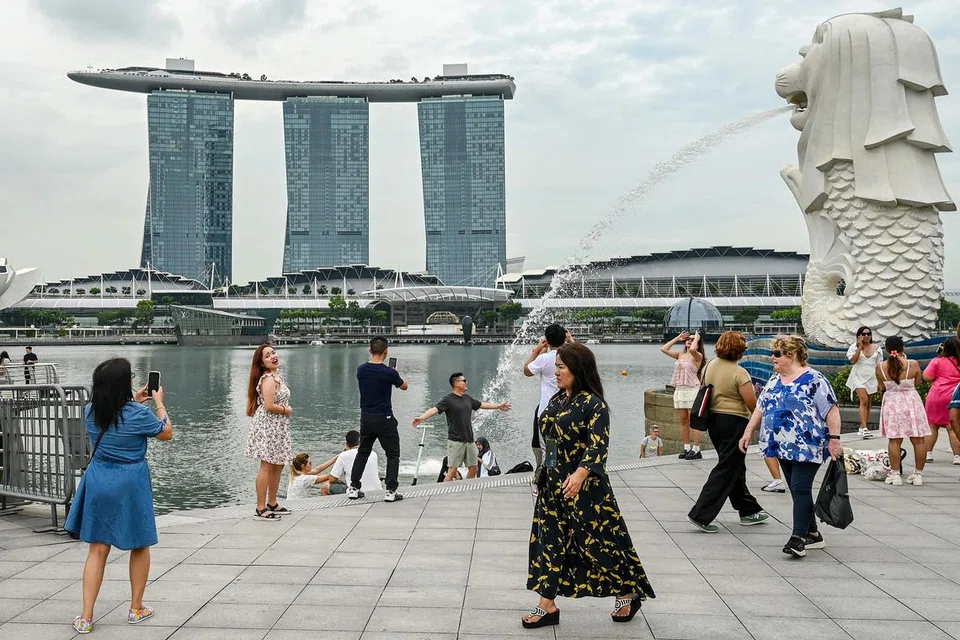 Pengunjung bergambar di patung Merlion berdekatan Marina Bay Sands pada Disember.