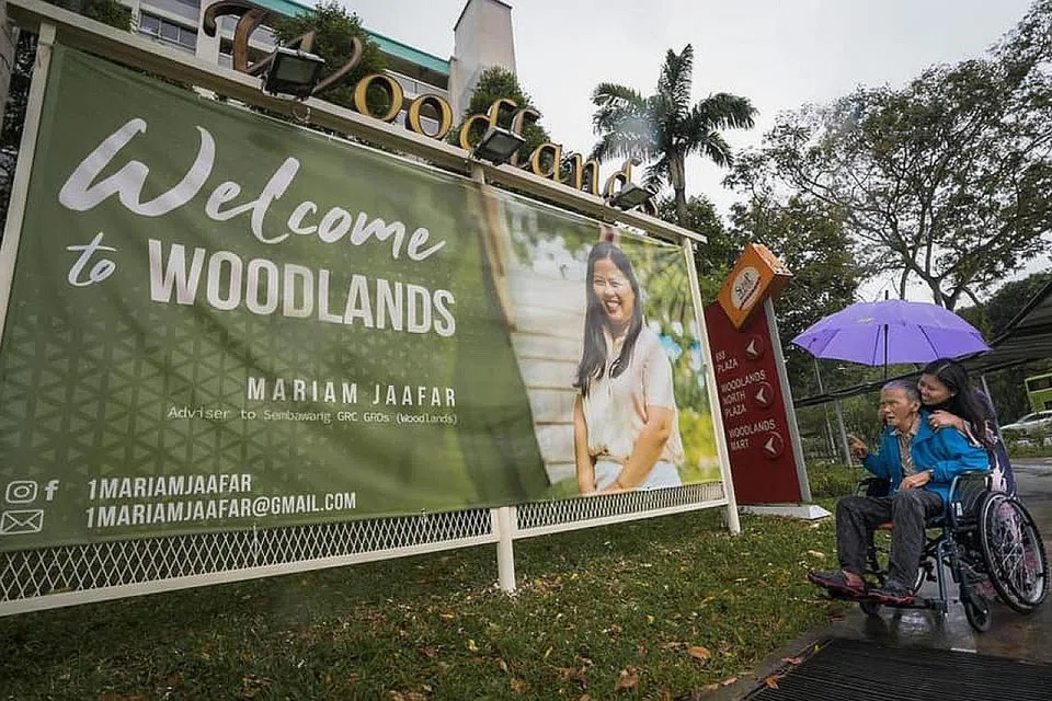 KENANGAN MANIS BERSAMA BAPA: Cik Mariam Jaafar membawa bapanya yang dikenali ramai sebagai Cikgu Jaafar Haron, melihat kain rentang yang dipasang di estet Woodlands di mana beliau berkhidmat sebagai Anggota Parlimen. - Foto FACEBOOK MARIAM JAAFAR