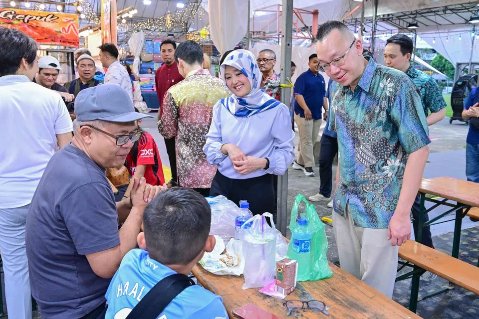 Anggota Parlimen GRC Jurong, Cik Rahayu Mahzam (dua dari kanan), yang juga Menteri Negara (Penerangan dan Pembangunan Digital merangkap Kesihatan); dan Dr Tan Wu Meng (depan, kanan), berinteraksi bersama pengunjung bazar. 