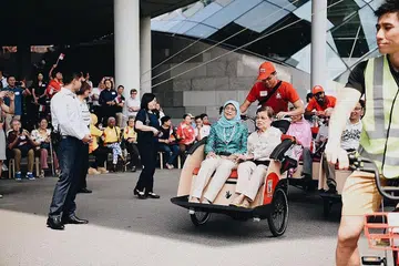 NAIK BECA BERSAMA: Presiden Halimah Yacob dan warga emas, Cik Tan Geok Hak, 90 tahun, naik beca bersama di Taman di Persisiran. Mereka dipandu sukarelawan belia, Encik Kester Yeo. - Foto TEMASEK FOUNDATION CARES
