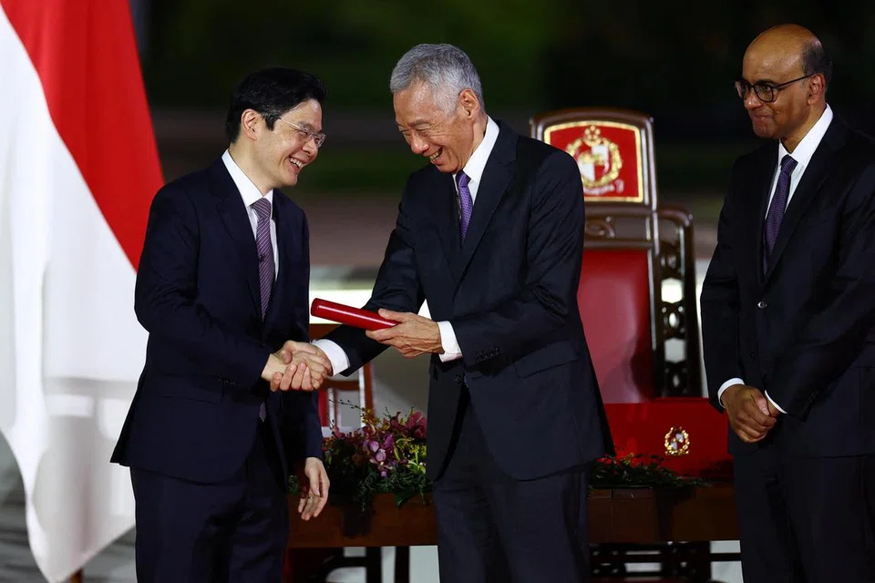 Perdana Menteri Singapura yang baru, Encik Lawrence Wong (kiri) berjabat tangan dengan Menteri Kanan, Encik Lee Hsien Loong, semasa upacara angkat sumpah sebagai Perdana Menteri Singapura keempat di Istana pada 15 Mei.