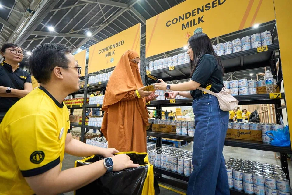 Cik Hadrawati Abdul Rahman, 50 tahun (dua dari kanan), memilih barangan seperti beras, susu dan kopi di Kindness Market. Beliau kadangkala terpaksa mengetepikan pembelian susu bagi mengutamakan perbelanjaan persekolahan anak-anak dan urusan perubatan.