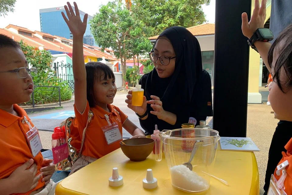 MINYAK ATAR: Kanak-kanak prasekolah berpeluang mencuba membuat minyak atar sendiri sambil dipantau oleh salah seorang pelajar Nafa (dua dari kanan). - Foto BH oleh SITI AISYAH NORDIN