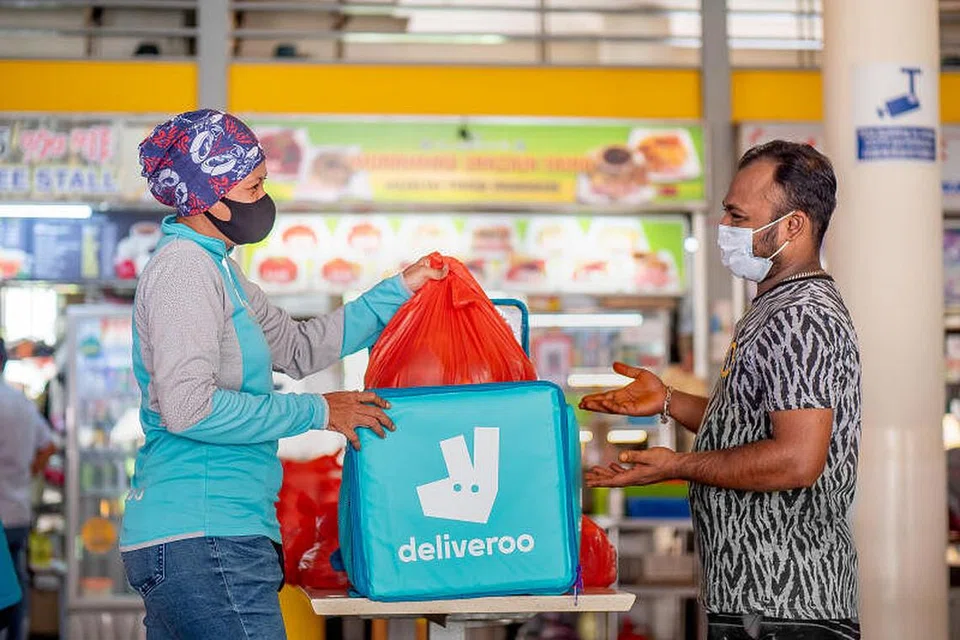 PENGHANTARAN ISTIMEWA 'DARI WIRA KEPADA WIRA': Cik Noryatti (kiri) mengambil makanan buka puasa dari gerai Muhammad Shazain Faiha Muslim Food Paradise di Pasar Tiong Bahru untuk dihantar kepada pekerja migran di dormitori. Beliau antara 30 penghantar makanan Deliveroo yang terlibat dalam satu inisiatif kempen 'Heroes to Heroes' Deliveroo.