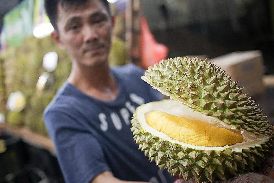 Sementara seorang pegerai (atas) menunjukkan mutu durian yang dijualnya. - Foto BH oleh ONG WEE JIN