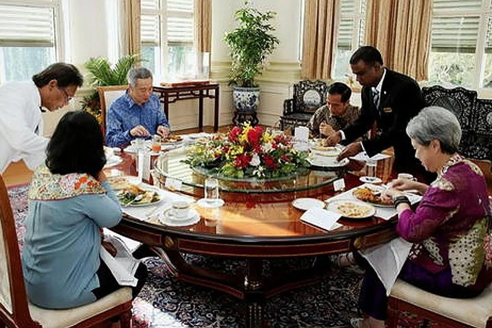 DIPLOMASI NASI LEMAK: Presiden Indonesia Joko Widodo (tiga dari kanan) dan isteri, Cik Iriana (membelakangkan kamera), menjamu nasi lemak daripada Selera Rasa Nasi Lemak di Adam Road bersama Encik Lee Hsien Loong (berkemeja biru) dan isteri, Cik Ho Ching (kanan) semasa lawatannya ke sini dua tahun lalu. - Foto MCI