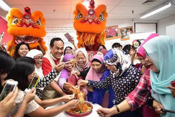 RAIKAN BERSAMA: Encik Shamsul (berbaju merah) bersama pembantu rumah asing ketawa riang melakukan sesi 'Lohei' bersama di CDE yang terletak di City Plaza semalam. - Foto BH oleh DESMOND WEE