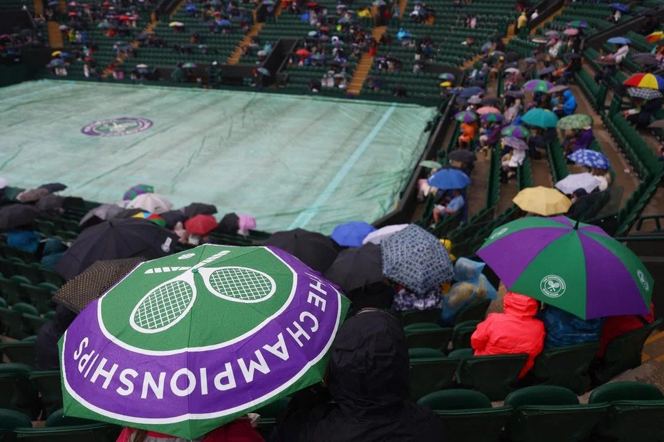 DIGANGGU CUACA:  Penonton menggunakan payung dan gelanggang terpaksa ditutup apabila hujan turun dalam perlawanan pusingan pertama antara Stefanos Tsitsipas dengan Dominic Thiem.