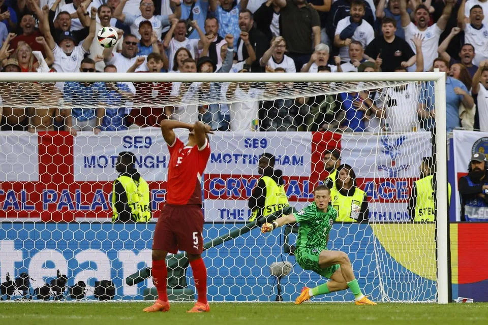 Pemain Switzerland, Manuel Akanji (tutup muka) begitu kecewa selepas sepakan penaltinya diselamatkan penjaga gol England, Jordan Pickford (kanan).