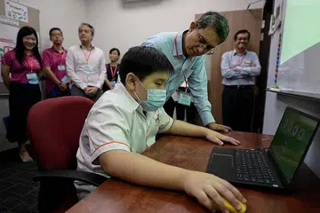 BERI LEBIH AKSES: Dr Faishal (tengah, berbaju biru) berinteraksi dengan pelajar Skye Tong, 10 tahun, (duduk) semasa perasmian Pusat Pembelajaran Yishun Persatuan Disleksia Singapura (DAS) yang baru semalam. - Foto BH oleh NG SOR LUAN