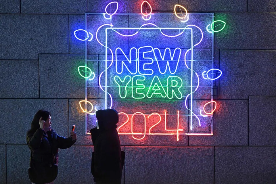LAMPU NEON: Dua individu dilihat mengambil gambar di depan paparan lampu neon ‘New Year 2024’ di Seoul, Korea Selatan, sempena tahun baru yang bakal menjelma.