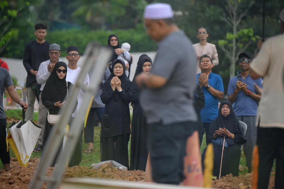 Cik Saniah Sali (kanan bawah), 79 tahun, ibu kepada Allahyarhamha Norzihan Juwahib, mangsa kedua dalam kemalangan di Tampines, sedang berdoa semasa pengebumian anaknya itu di Pusara Aman pada 23 April.