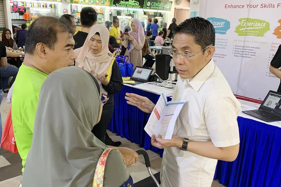 DEKATI MASYARAKAT: Dr Maliki (berbaju putih) menerangkan tentang SkillsFuture kepada pengunjung ke Pasar Geylang Serai semasa 'roadshow' yang diadakan di sana Sabtu lalu. - Foto SOUTH EAST CDC