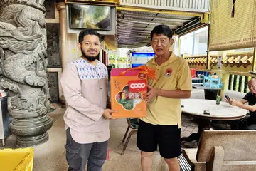 Pegawai agama masjid (MRO) Masjid Al-Islah, Ustaz Uwais Al-Qarni Mohamed Fawzi (kiri), memberi hamper kepada kakitangan kuil Sheng Jia sempena Tahun Baru Cina.