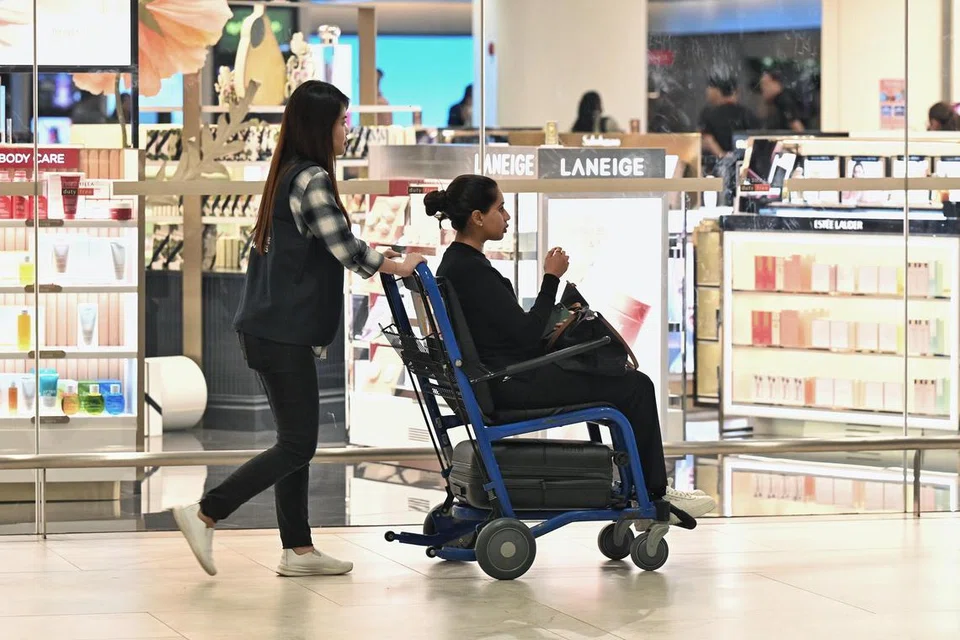 Seorang penumpang yang dilihat tiba di dewan ketibaan dengan ditolak dalam kerusi roda. 