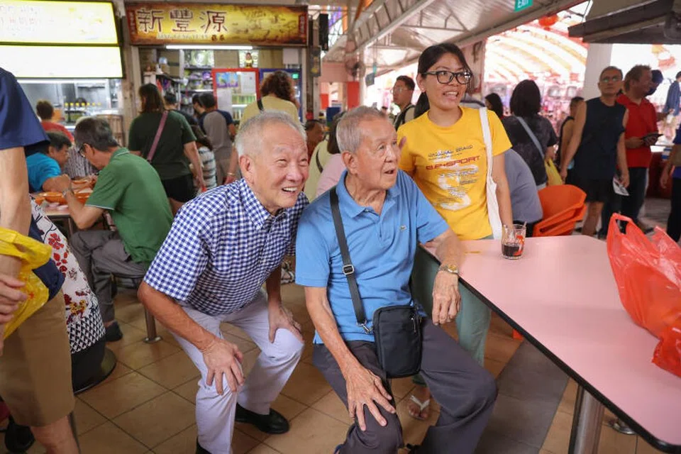 BERAMAH MESRA: Beberapa penduduk yang sedang menikmati sarapan mereka di Pusat Makanan Chong Pang tidak melepaskan peluang bergambar dengan calon Pilihan Raya Presiden, Encik Ng Kok Song, semasa kunjungannya ke sana pada Sabtu.