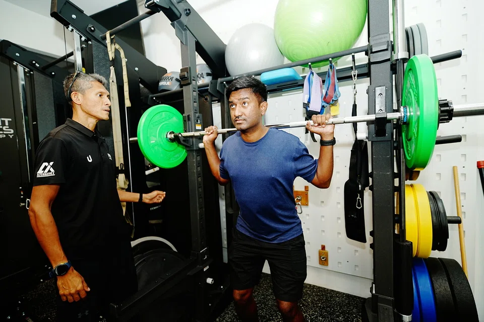 Pengasas Fabian Williams Coaching Concepts (FWCC) dan Movement Mechanics, Encik Fabian Williams (kiri) melatih seorang pengguna gimnasium di pusat Alternative X yang terletak di 7 Jalan Saudara Ku pada 9 Oktober.