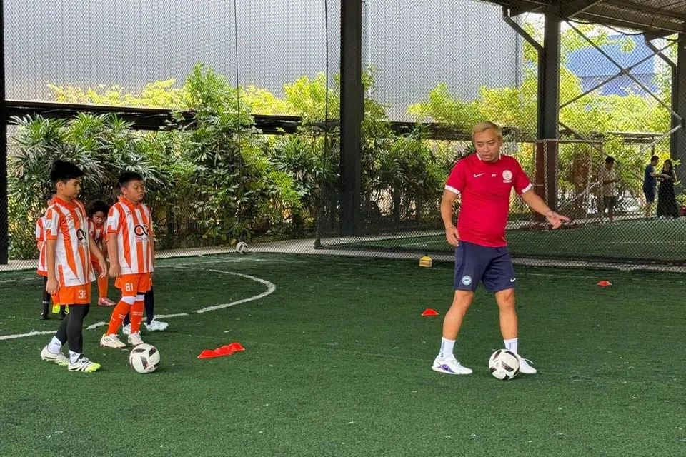 Encik Roslee Tay (kanan) semasa sesi latihan bola sepak di Football Code Academy di Iskandar Puteri, Johor.