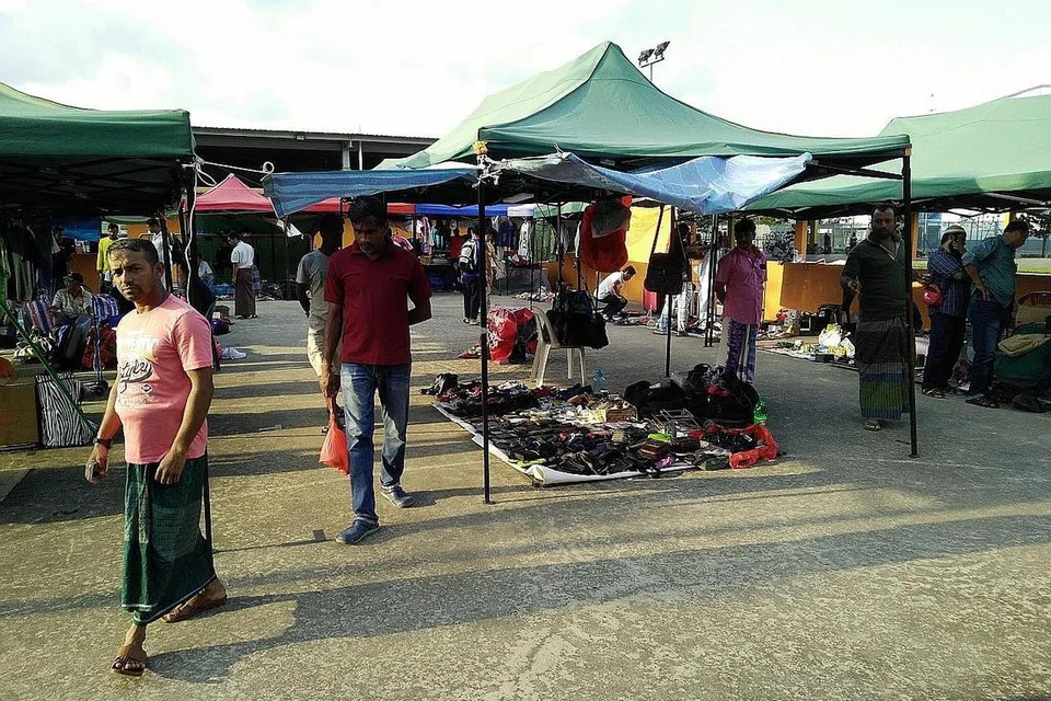 TUMPUAN PEKERJA ASING: Pekerja asing keluar beramai-ramai daripada domiteri masing-masing untuk membeli barang-barang terpakai di Woodlands Recreation Centre. - Foto SAINI SALLEH.