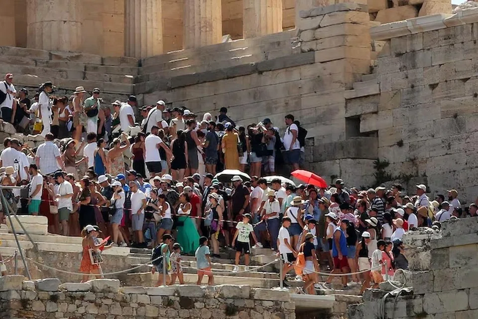 MENUNGGU DI TENGAH PANAS: Pelancong melawat Acropolis terpaksa menunggu dalam suasana panas apabila monumen Acropolis tutup buat sementara akibat cuaca panas di Athens, Greece. Kakitangan Palang Merah mengagihkan botol air sementara pelancong menunggu. 