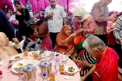 GEMBIRAKAN WARGA SENJA: Puan Halimah mengedarkan hadiah kepada hadirin jamuan acara Sunlove. - Foto SUNLOVE