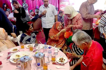 GEMBIRAKAN WARGA SENJA: Puan Halimah mengedarkan hadiah kepada hadirin jamuan acara Sunlove. - Foto SUNLOVE
