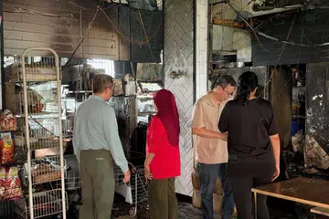 Encik Lee Hong Chuang bersama beberapa pegerai, melihat sisa kebakarang di kedai kopi.