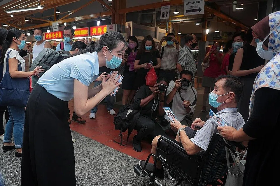 TEMUI PENDUDUK: Calon Parti Pekerja (WP) bagi GRC East Coast, Cik Nicole Seah (kiri) menemui penduduk bersama pasukannya di Bedok North semalam. - Foto BH oleh JASON QUAH