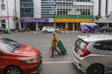 GUGAT EKONOMI: Penularan koronavirus menjejas negara-negara sedunia termasuk negara-negara anggota Asean. Kelihatan seorang pekerja pembersihan mengenakan pelindung muka semasa bekerja di jalan raya di Medan, Sumatra Utara, Indonesia,