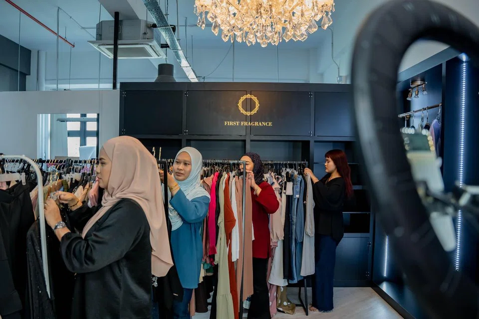 Pengasas Mayfifth.sg, Cik Marziani Mohd Jalil (kiri), bersama kakitangannya menyiapkan pakaian yang akan dijual ketika sesi ‘live’ di gudangnya.