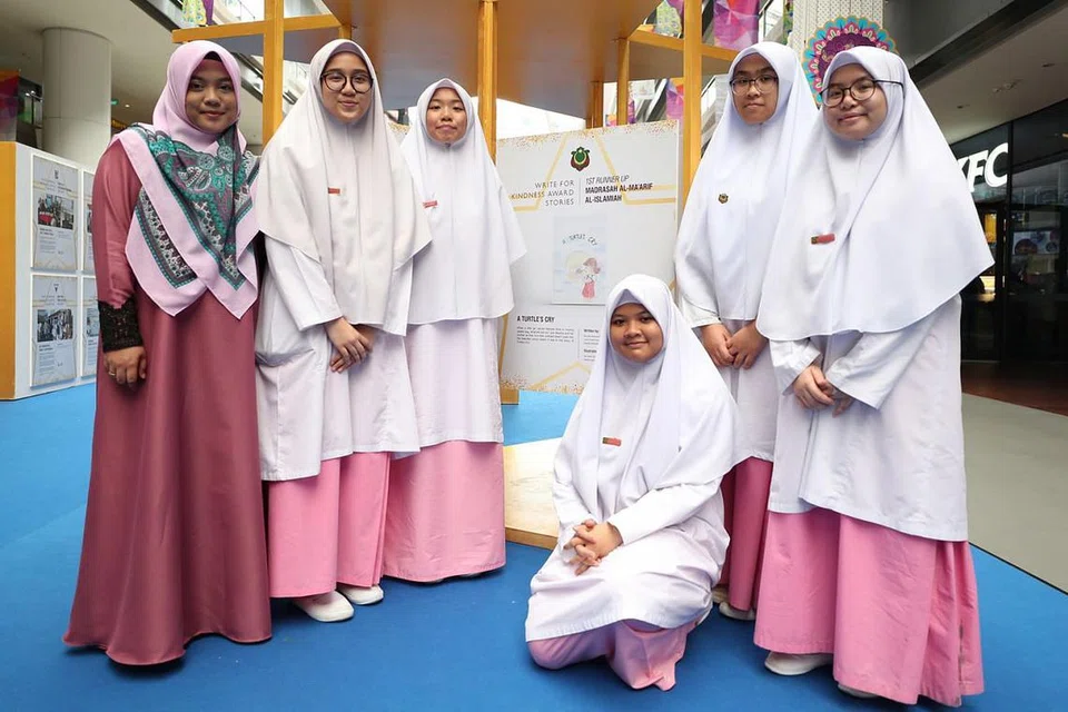 INGIN KANAK-KANAK SEMAI KEBAIKAN DARI AWAL: (Dari kiri) Cik Nur Wahidah Hashim, guru Madrasah Al-Ma'arif Al-Islamiah, bersama pelajarnya Nur-Riny Ashmooni Mohamed Roslan, Dina Nazirin, Fairuz Shafa Nurulaini, Aeisyah Mohamed Zaki dan Harissa Qistina Suwandi. Buku yang ditulis pelajar ini menerapkan nilai-nilai kebaikan kepada pembacanya. - Foto BH oleh BENJAMIN SEETOR