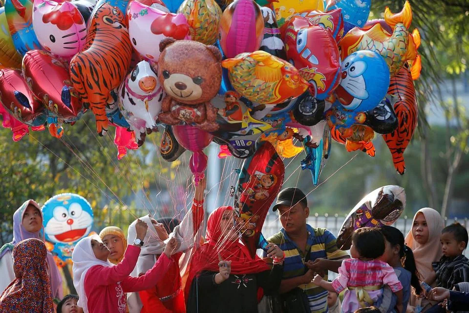 DI JAKARTA: Kanak-kanak membeli belon berwarna-warni selepas solat Hari Raya di Pelabuhan Sunda Kelapa di Jakarta, Indonesia, kelmarin. - Foto REUTERS