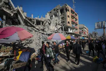 Para penduduk Palestin berkunjung ke gerai yang didirikan bersebelahan bangunan-bangunan yang runtuh dekat kem pelarian Nuseirat pada 11 Mac.