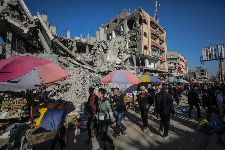 Para penduduk Palestin berkunjung ke gerai yang didirikan bersebelahan bangunan-bangunan yang runtuh dekat kem pelarian Nuseirat pada 11 Mac.