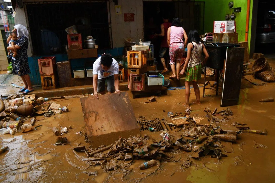 Seorang penduduk membersihkan rumah  selepas ia dinaiki air di sebuah kampung di Manila pada 25 Julai, sehari selepas hujan lebat yang dibawa oleh taufan Gaemi.