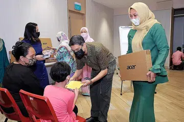 BAWA KECERIAAN: Dr Faishal dan Cik Haslinda memberikan komputer riba tajaan Far East Organisation kepada sekumpulan anak-anak pesalah dadah semasa acara Projek Pelita Hati di Kelab Masyarakat Nee Soon Central semalam. - Foto BM oleh KHALID BABA