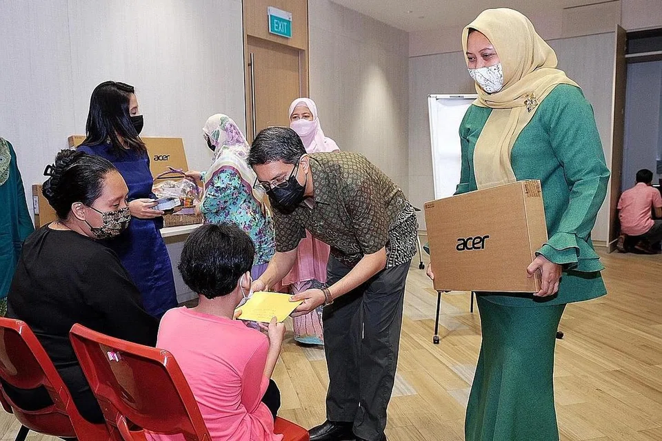 BAWA KECERIAAN: Dr Faishal dan Cik Haslinda memberikan komputer riba tajaan Far East Organisation kepada sekumpulan anak-anak pesalah dadah semasa acara Projek Pelita Hati di Kelab Masyarakat Nee Soon Central semalam. - Foto BM oleh KHALID BABA