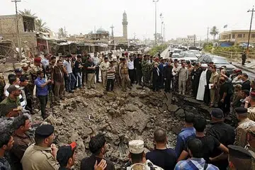 KAWAH AKIBAT LETUPAN BOM KERETA: Penduduk dan pasukan keselamatan Iraq berhimpun di kawah berukuran kira-kira lima meter lebar dan dua meter dalam akibat letupan bom kereta di pasar di Khan Bani Saad, Baghdad, semasa sambutan Hari Raya Aidilfitri. - Foto Reuters.