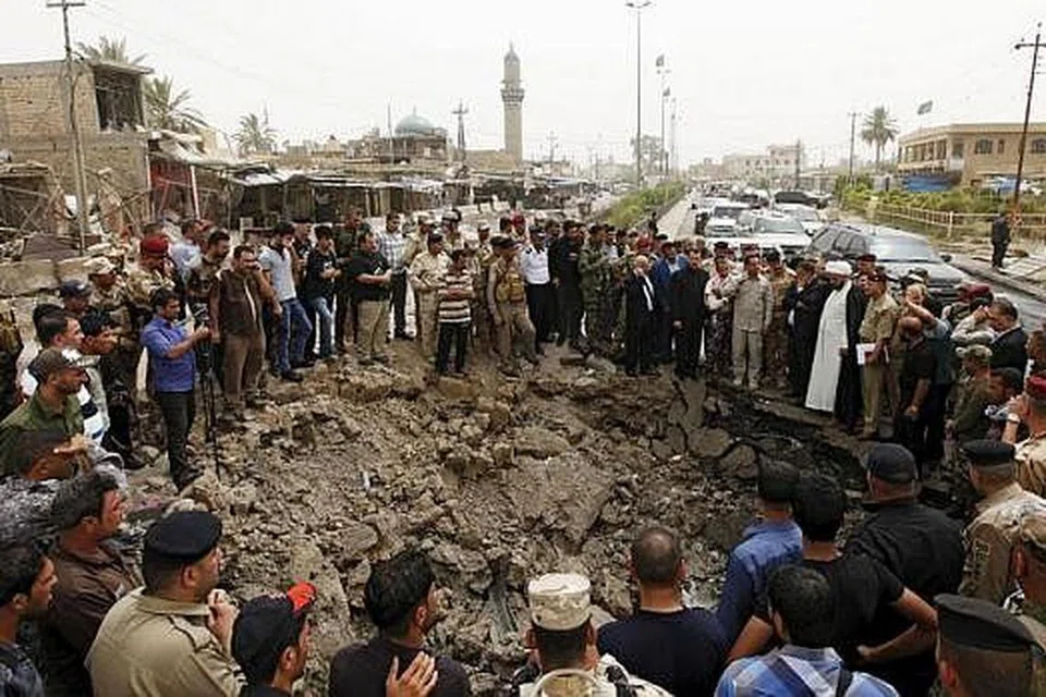 KAWAH AKIBAT LETUPAN BOM KERETA: Penduduk dan pasukan keselamatan Iraq berhimpun di kawah berukuran kira-kira lima meter lebar dan dua meter dalam akibat letupan bom kereta di pasar di Khan Bani Saad, Baghdad, semasa sambutan Hari Raya Aidilfitri. - Foto Reuters.