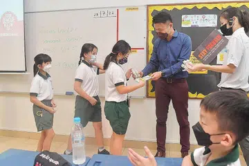 CEGAH DENGGI: Setiausaha Parlimen Kanan (Kemampanan dan Alam Sekitar), Encik Baey Yam Keng (baju biru), mengagih bahan penghalau nyamuk di Sekolah Rendah Pei Tong