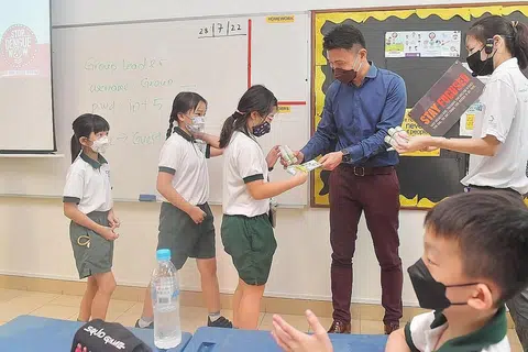 CEGAH DENGGI: Setiausaha Parlimen Kanan (Kemampanan dan Alam Sekitar), Encik Baey Yam Keng (baju biru), mengagih bahan penghalau nyamuk di Sekolah Rendah Pei Tong
