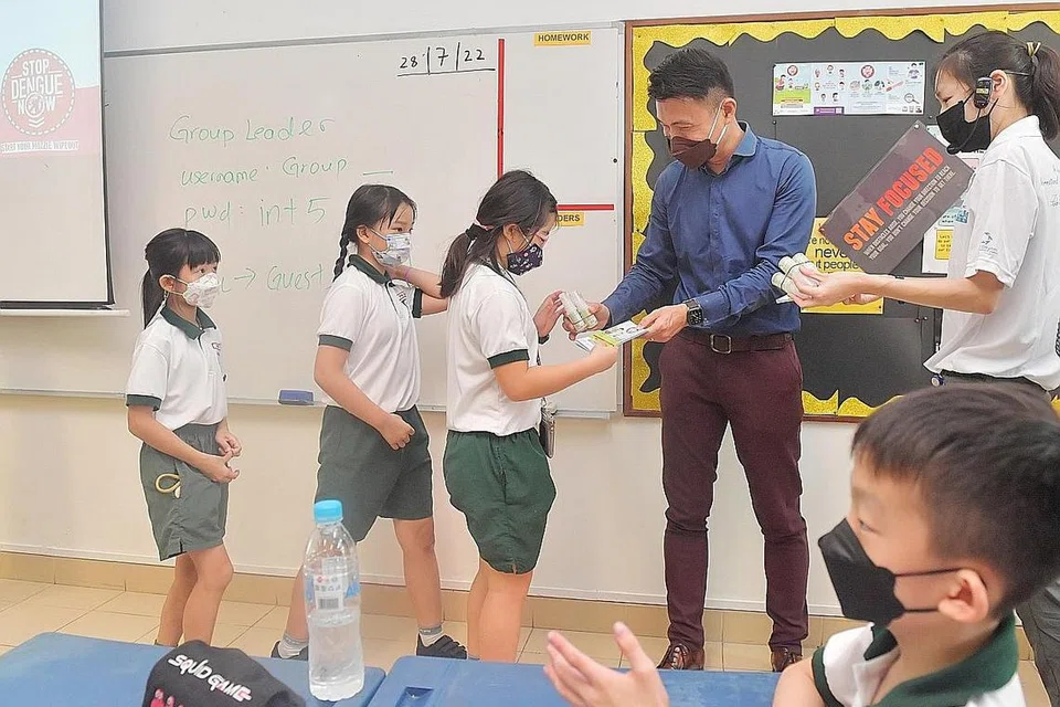 CEGAH DENGGI: Setiausaha Parlimen Kanan (Kemampanan dan Alam Sekitar), Encik Baey Yam Keng (baju biru), mengagih bahan penghalau nyamuk di Sekolah Rendah Pei Tong