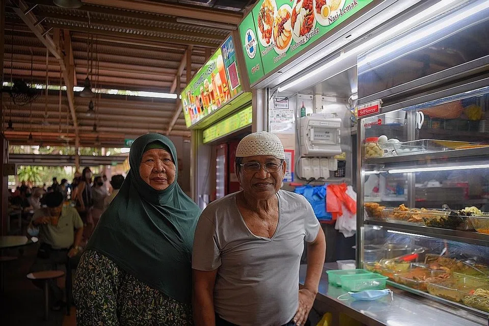 PERNIAGAAN TURUN-TEMURUN: Cik Azizah Abdullah, yang kini dibantu suaminya, Encik Abdul Karim, dan pekerja lain merancang menyerahkan gerainya di Pusat Makanan Ghim Moh kepada cucunya kelak. - Foto BM oleh MARK CHEONG