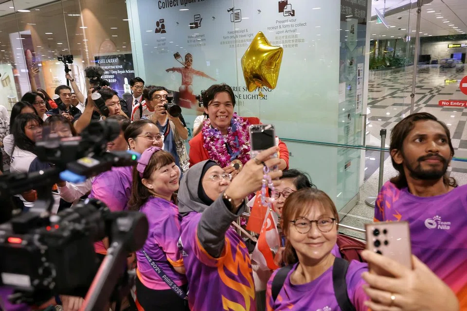 Maeder (tengah) bergambar dengan para penyokong yang hadir di Terminal 3 Lapangan Terbang Changi seawal 5.30 pagi pada 13 Ogos untuk menyambutnya pulang.