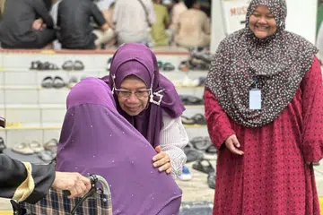 Kakitangan Masjid Darul Makmur, Ustazah Suhanah Ahmad (tengah), bersama anggota Lembaga Pentadbir Masjid, Cik Jamilah Mohd Amran (kanan), menerima kedatangan jemaah dengan tangan terbuka.