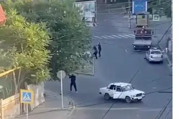 Kelihatan lelaki bersenjata sedang melakukan tembakan dari arah sebatang jalan raya di Makhachkala, Russia.