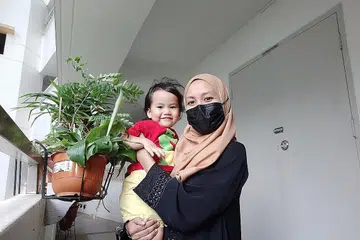 "Di dalam lif, saya mengajak anak saya melambaikan tangan kepada jiran lain yang ada di dalam lif juga, dan tunjukkannya cara hidup berjiran, seperti menahan pintu lif untuk jiran lain masuk, dan memberi laluan kepada jiran yang mahu keluar. Di taman permainan, saya senyum kepada kanak-kanak lain (saya harap mereka dapat lihat senyuman saya melalui mata saya), dan berkata "Hello!" dan mengajak mereka berbual. Saya galakkan anak saya bermain dengan mereka jika dia mahu tetapi tidak memaksa kerana saya faham pasti tidak mudah untuk dia tiba-tiba bermain dengan orang lain.'' - Penulis, Nur Dhuha Esoof (gambar atas), bersama anaknya, Munawwarah Mohammad Hanafi. - Foto ihsan NUR DHUHA ESOOF