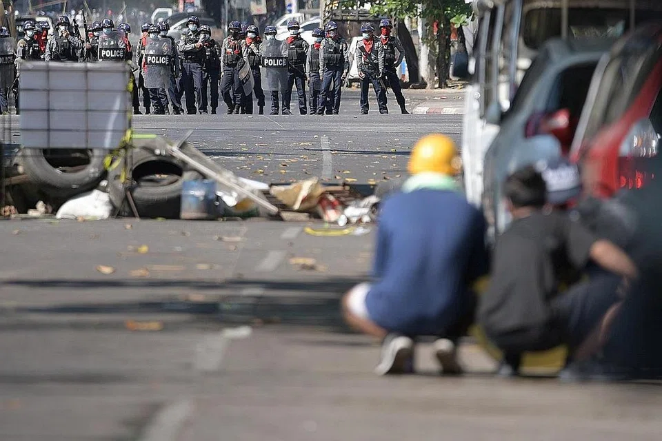 TUNGGU DAN LIHAT: Penunjuk perasaan berlindung di belakang kenderaan sambil menantikan tindakan selanjutnya polis rusuhan di Yangon semalam. - Foto REUTERS 
