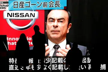 TANGKAPAN TERGEMPAR: Orang lalu lalang sedang sebuah monitor besar menayangkan berita siap dengan gambar Encik Carlos Ghosn dikenakan tuduhan dan ditangkap lagi di Tokyo pada 9 Disember lalu. - Foto REUTERS