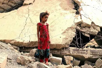 A Yemeni girl who was displaced with her family, stands amidst the rubble of a building that was destroyed in the civil war, in the district of Abs in Yemen's northwestern Hajjah province. - Photo AFP